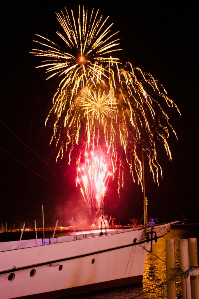 Vibrant fireworks light up the night sky over boats on Lake Geneva, Switzerland.