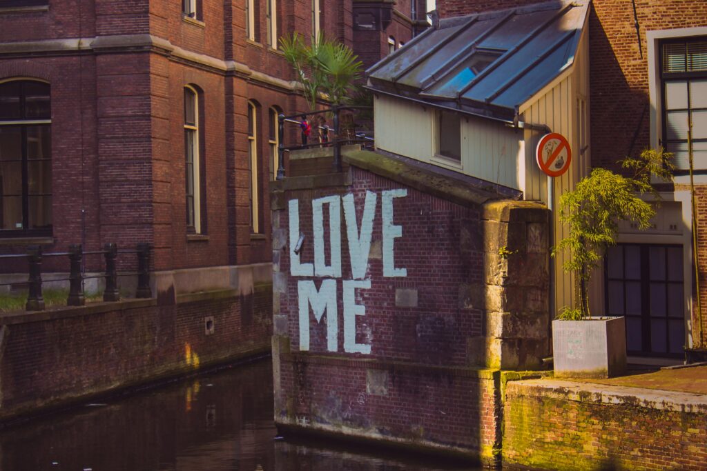 Brick wall with 'LOVE ME' graffiti by a canal in Amsterdam, Netherlands.